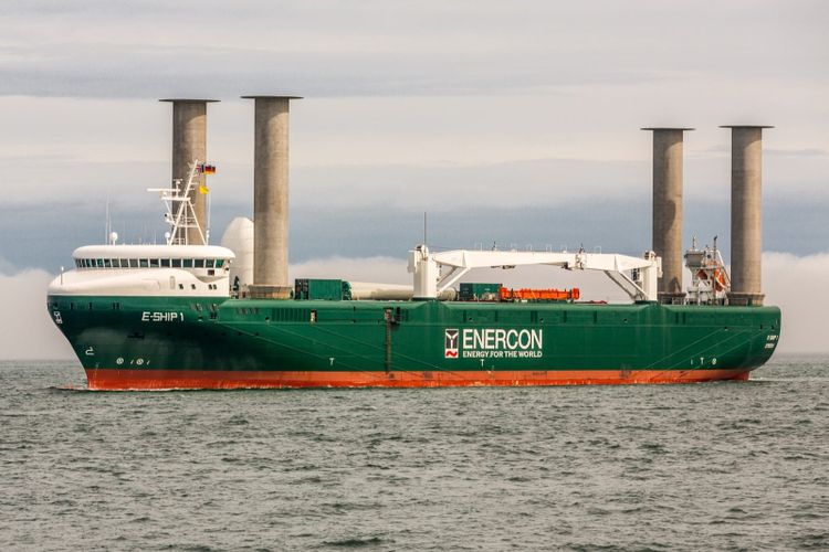 E Ship 1, a green hulled cargo ship with four tall grey rotor sail cylinders standing on her deck, at sea