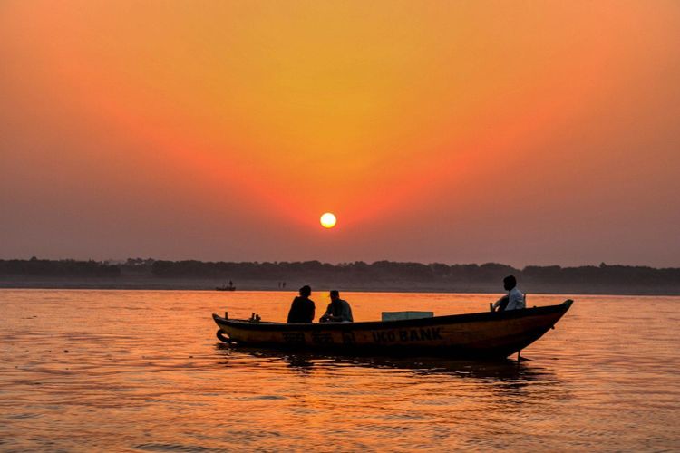 A wooden boat on a wide Indian river at sunset