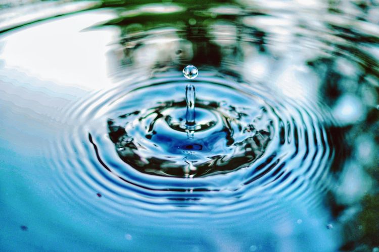 A single drop of water falling into still water, sending out rings