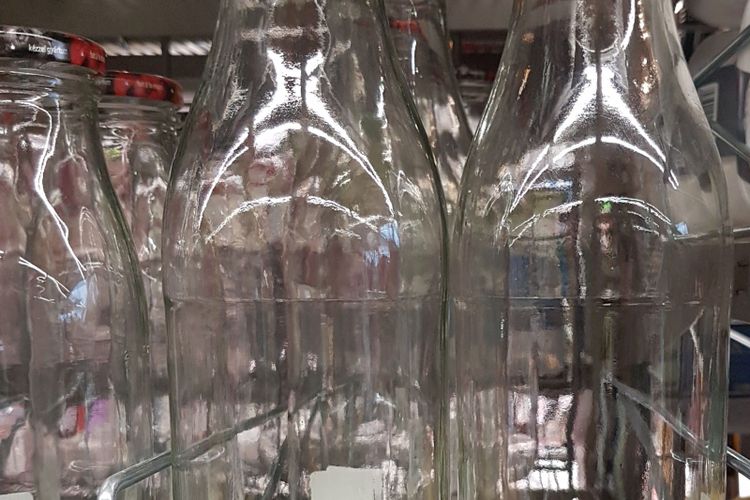 Rows of empty clear glass milk bottles standing in a crate