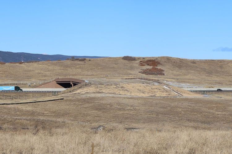 A wide earth covered bridge crossing a six lane highway