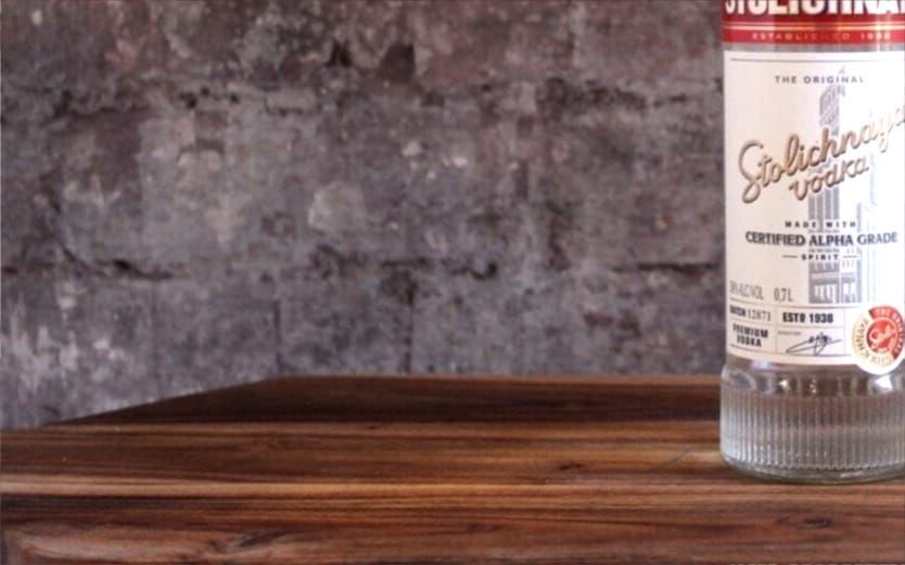 A bottle of Stolichnaya vodka on a wood table.