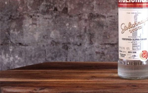 A bottle of Stolichnaya vodka on a wood table.