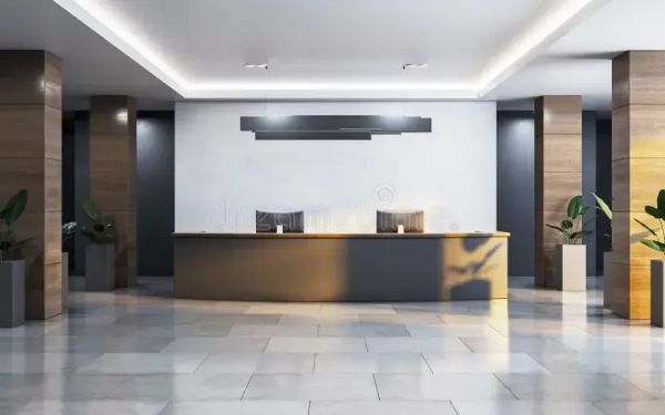 A lobby. A counter has two computer monitors on it. The tiles aren't exactly cream colored, but close enough.