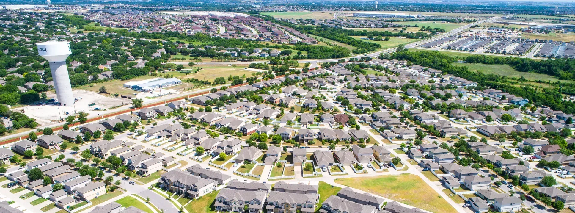Plugerville Aerial with Water Tower in the Left Side of Image. Suburban Homes Spread Out Across the Remainder of Image. 