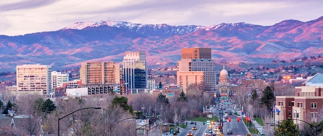 Skyline of Boise, Idaho including shot of the Capitol building. Snow-capped Boise Mountains in the background and major roads leading into the city in the foreground. 