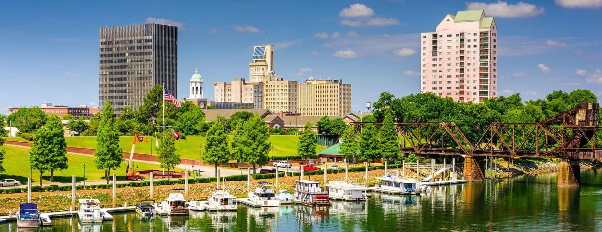 Pretty Daytime Image of the Augusta Georgia Skyline on the Shore of the Savannah River. Boats docked at the side of the river in the foreground and taller buildings in the background. 