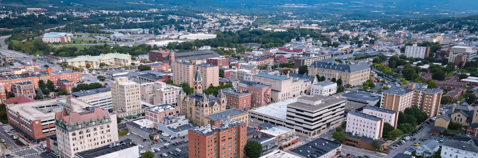 Aerial View of Scranton, Pennsylvania with Scranton City Hall prominent in the Center of Image. Suburbs stretch out in the background of the image. 