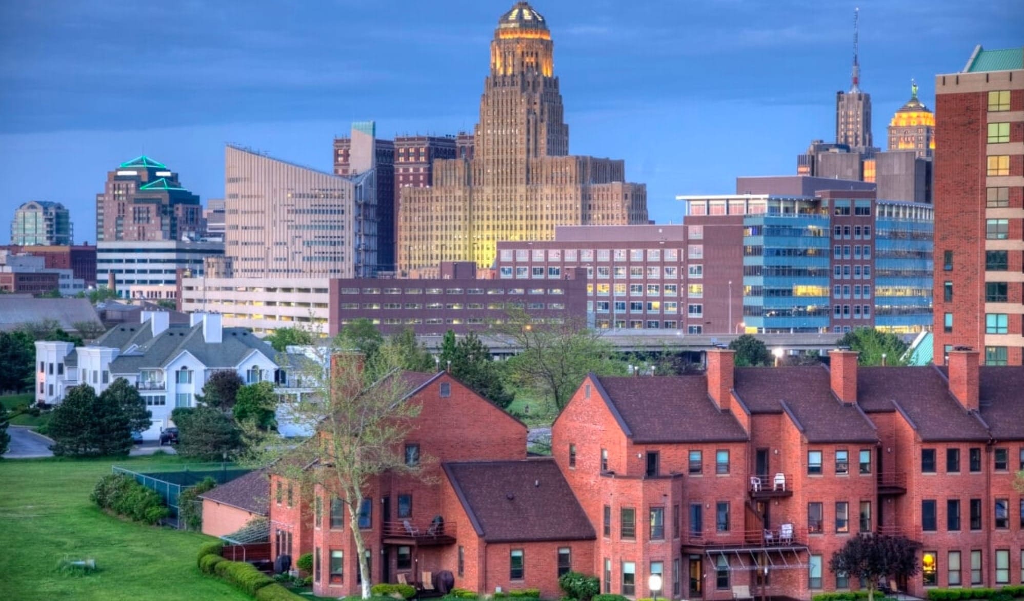 Beautiful Skyline of Buffalo, New York. Brick apartment building in the foreground and the skyrises of the city are in the center and background as the sun sets. 