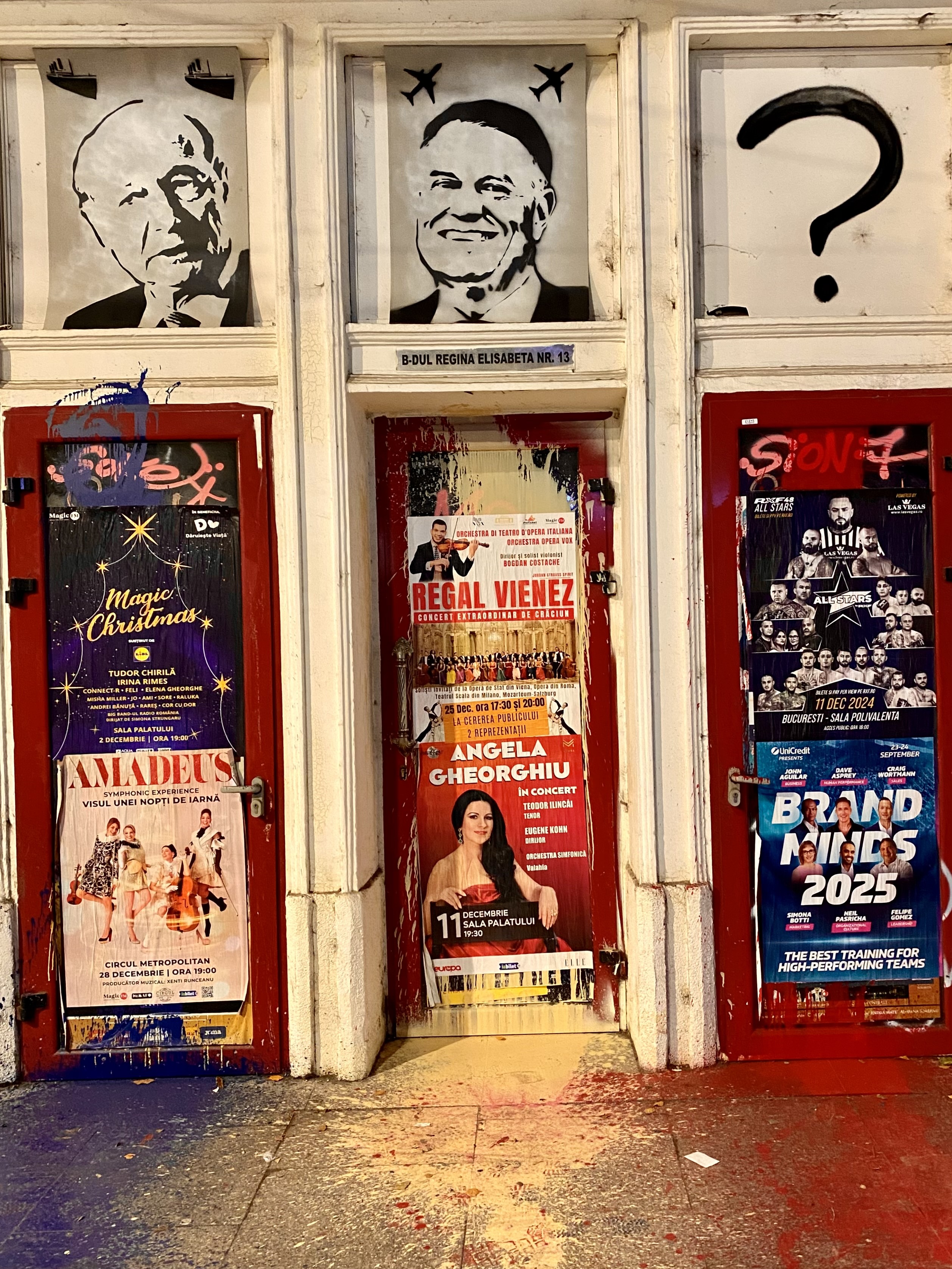 Two former presidents sketched on the wall of a storefront, with paint splattered on the asphalt.