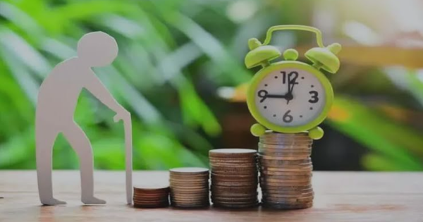 Figura de una persona mayor junto a un reloj despertador sobre pilas de monedas