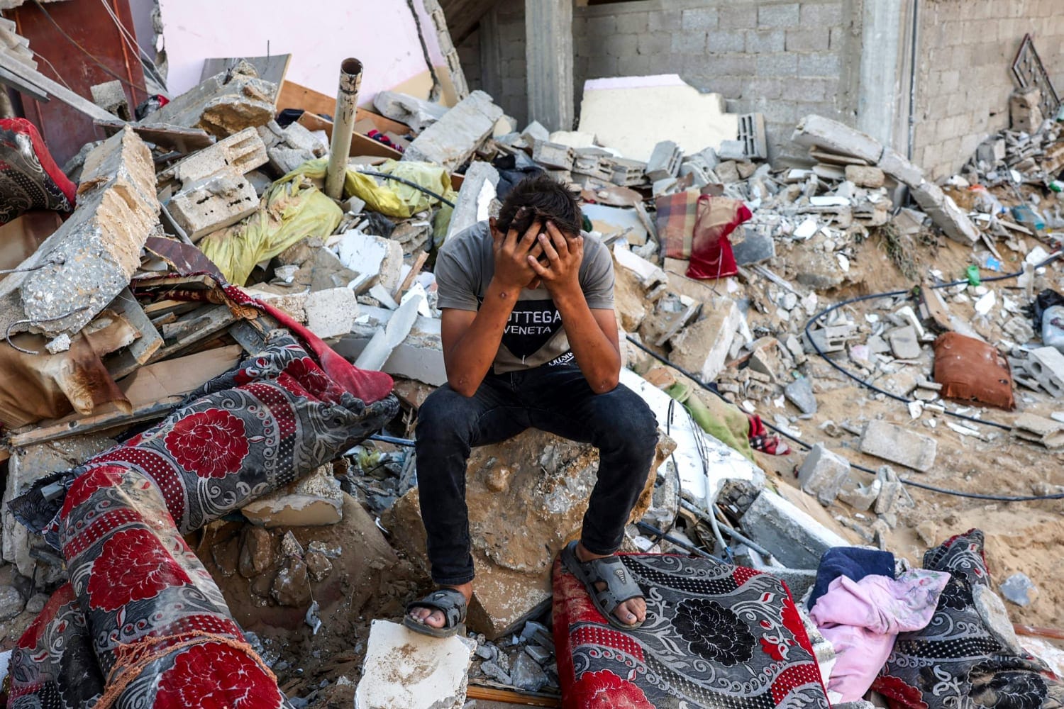 A young man sat with his head in his hands in Gazan rubble