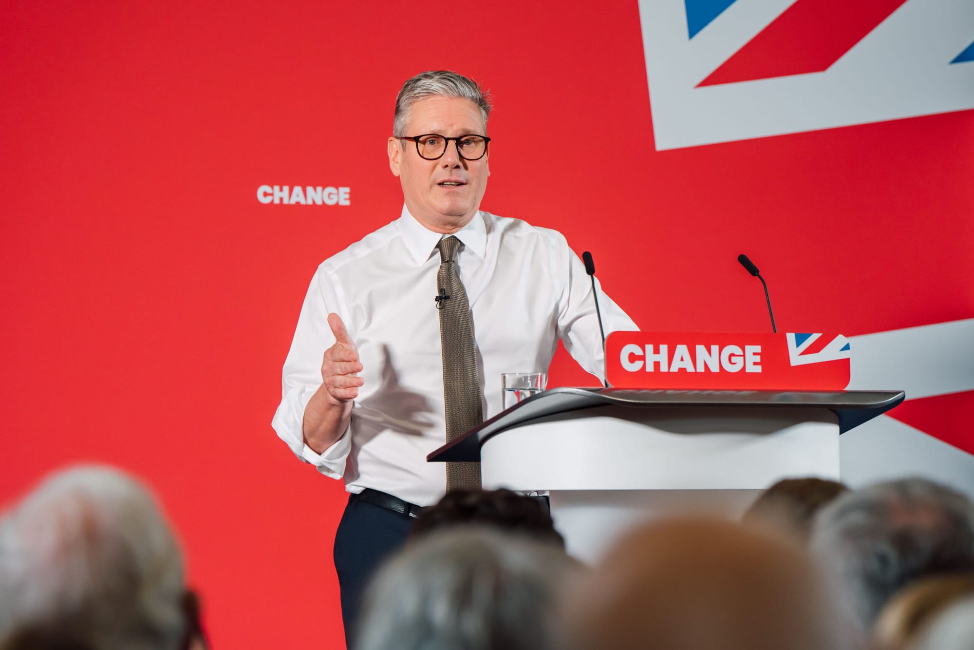 Keir Starmer stands in front of a red, white and blue background that bears the word CHANGE. On his lecturn is a panel that says CHANGE.