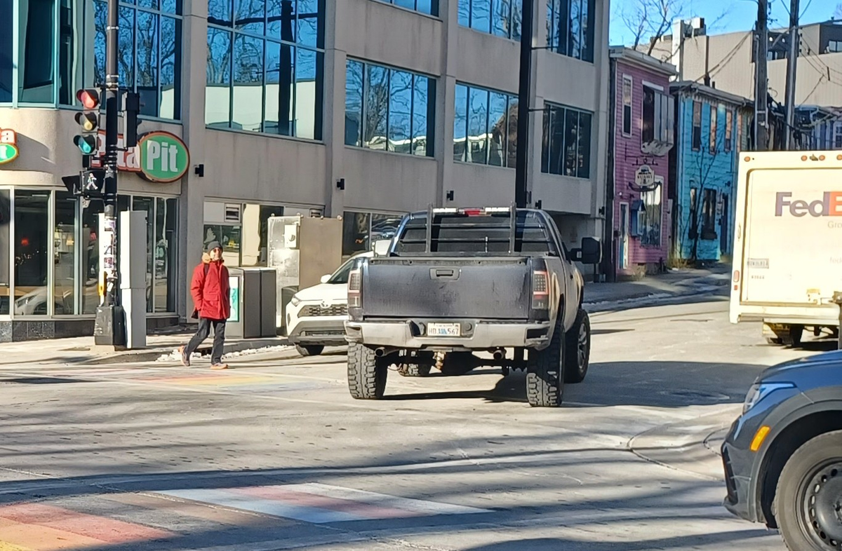 A street with a black truck turning into the path of a person legally crossing. Image credit: Vision Zero Kjipuktuk-Halifax