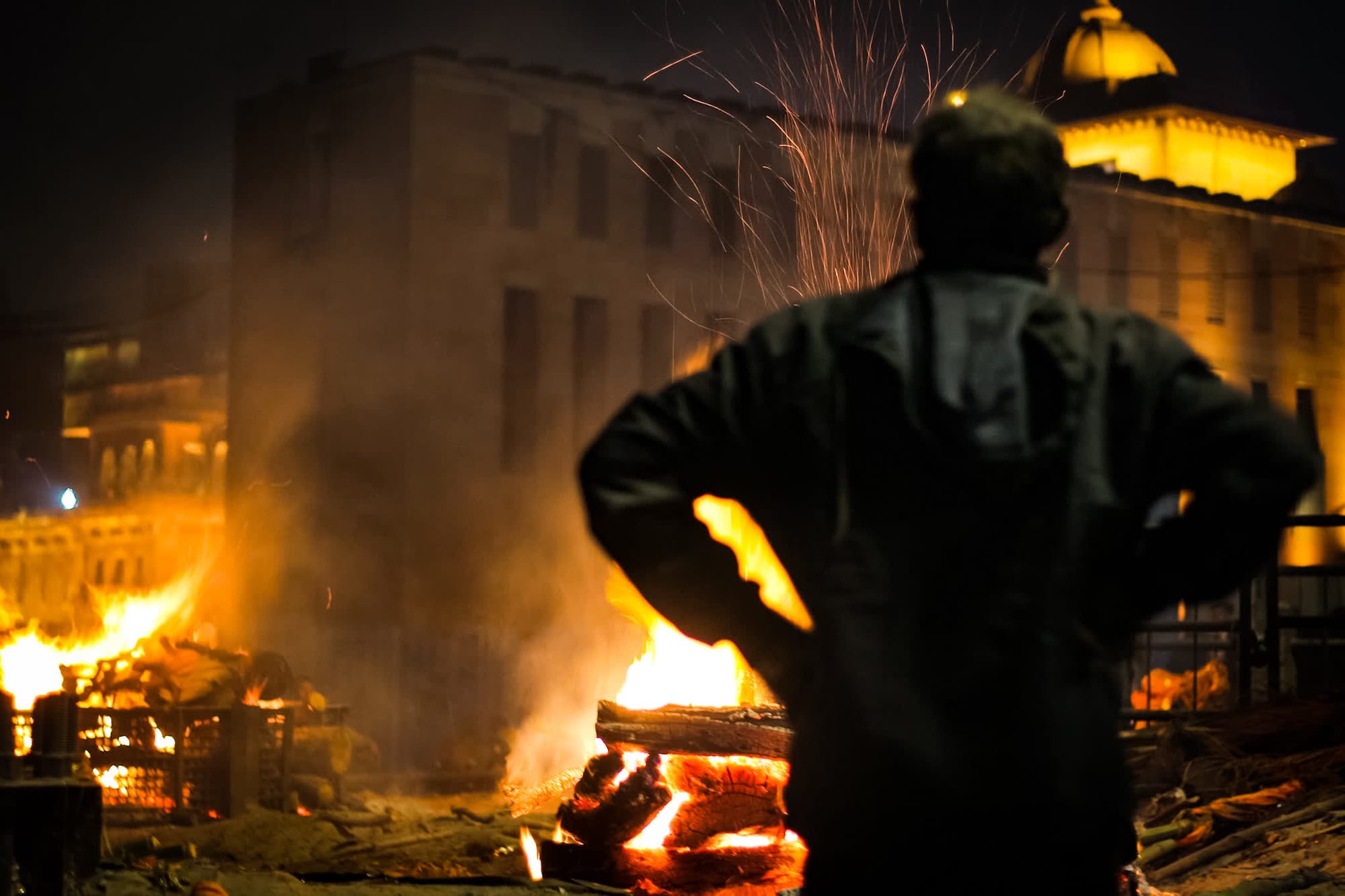 Photograph by Shreesh — a lone figure before the fires of Manikarnika, Banaras