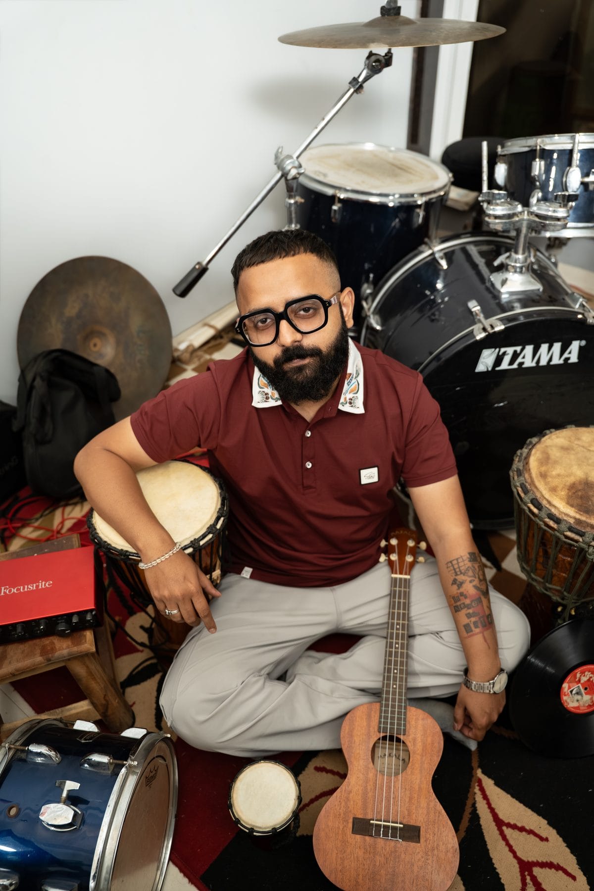 Jyotiraditya Bhujang surrounded by his instruments — drums, bongos, and a ukulele