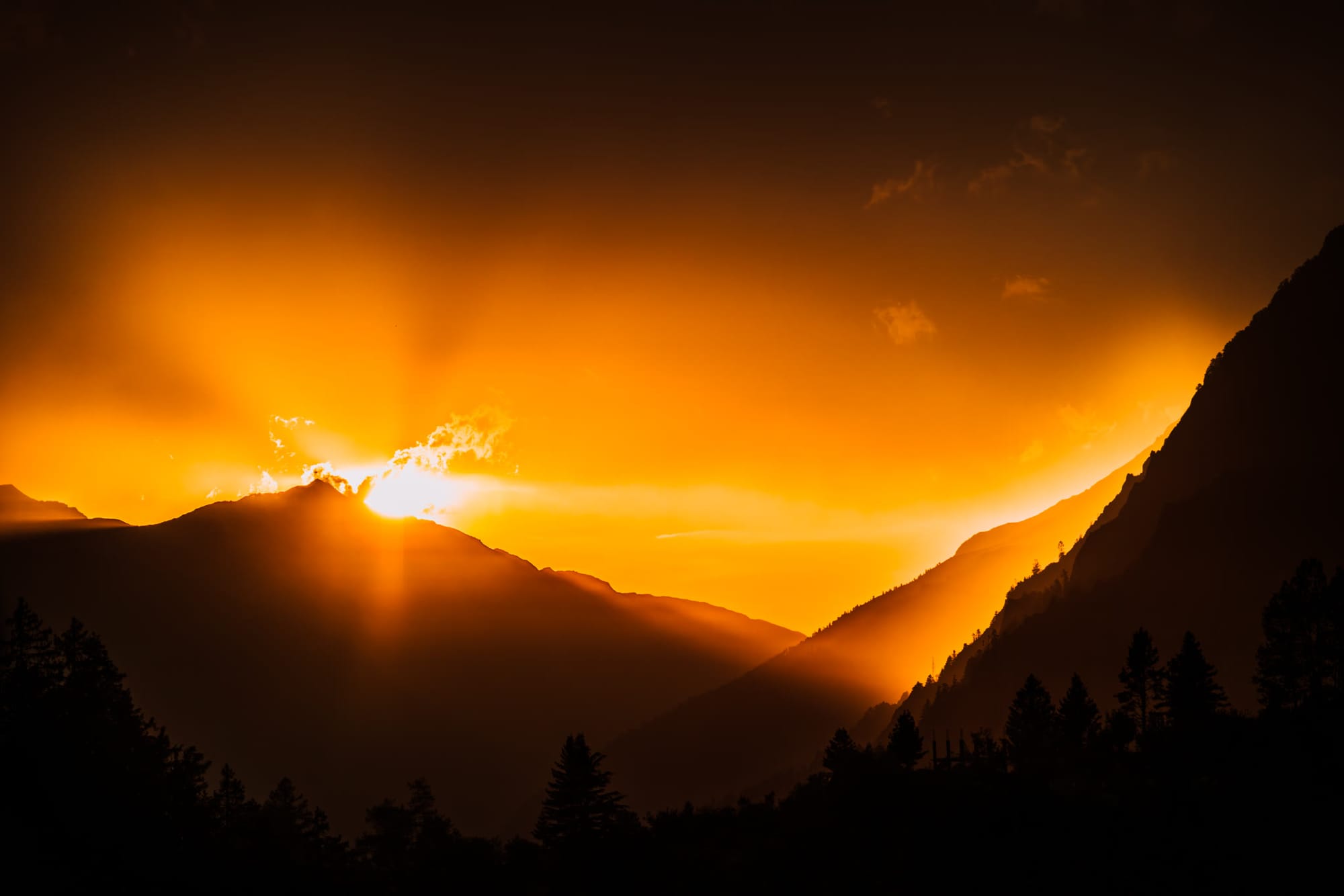 The sun bursting over a mountain ridge at golden hour