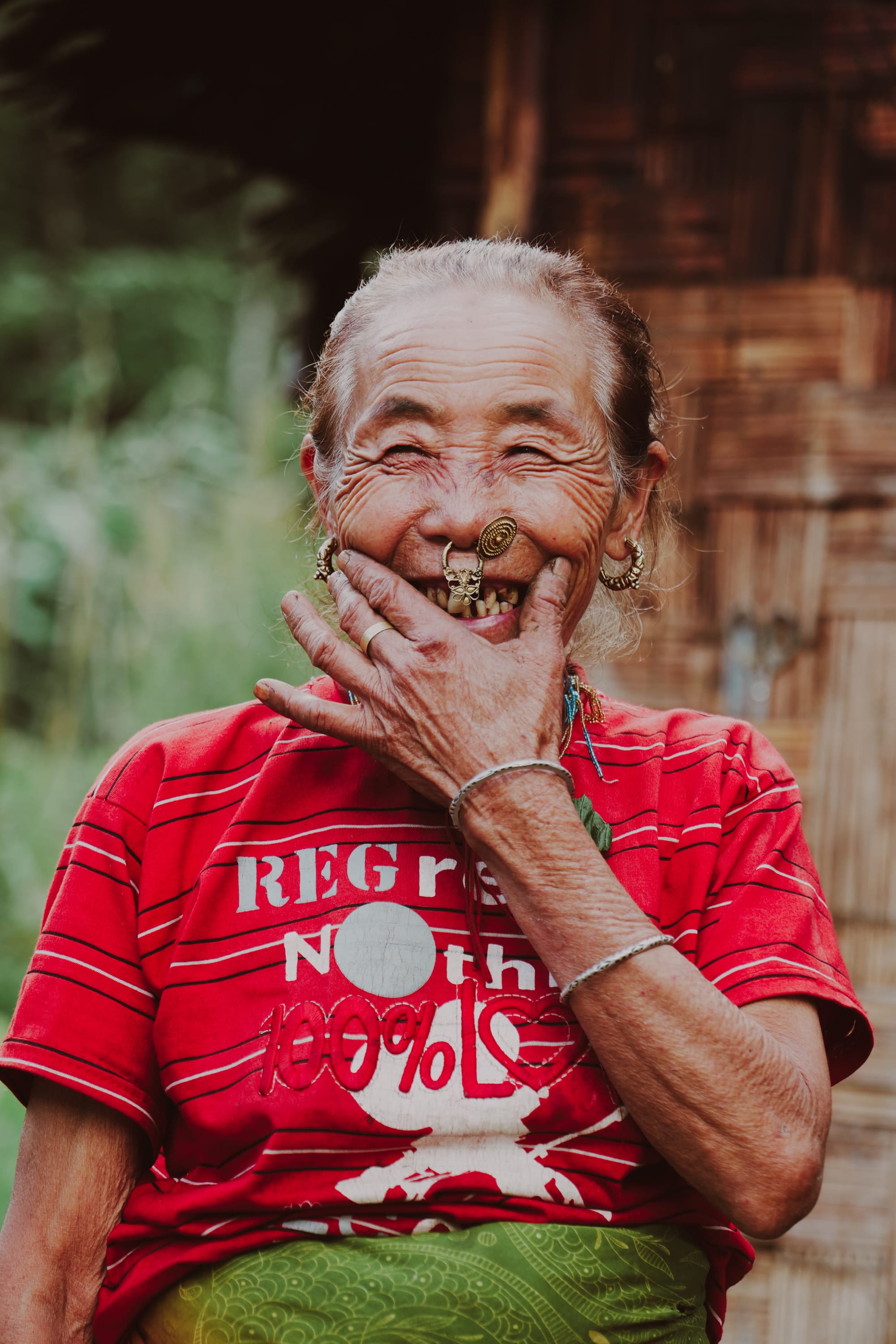 An elderly woman laughing warmly, hand raised to her face