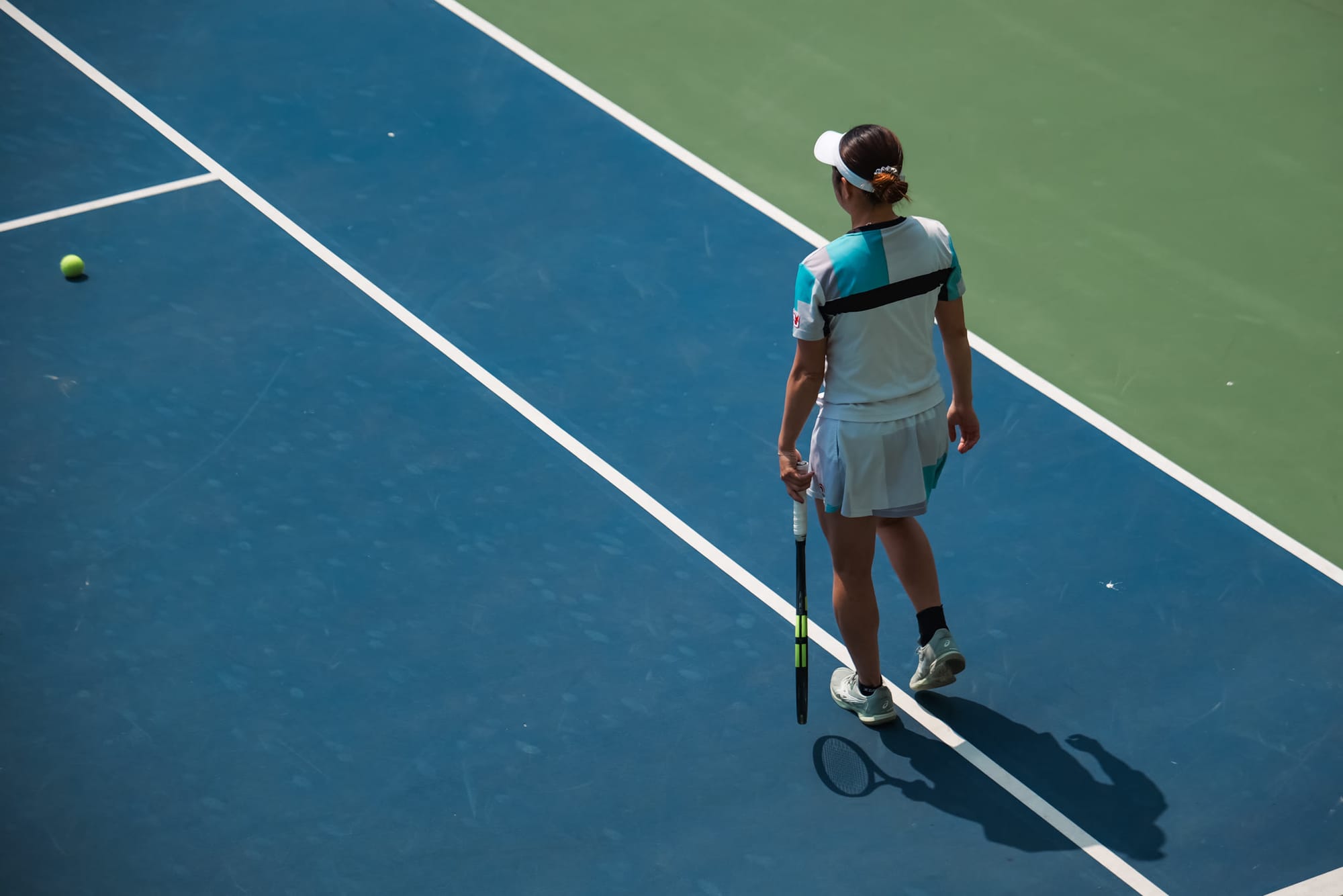 A tennis player alone on court, captured mid-match