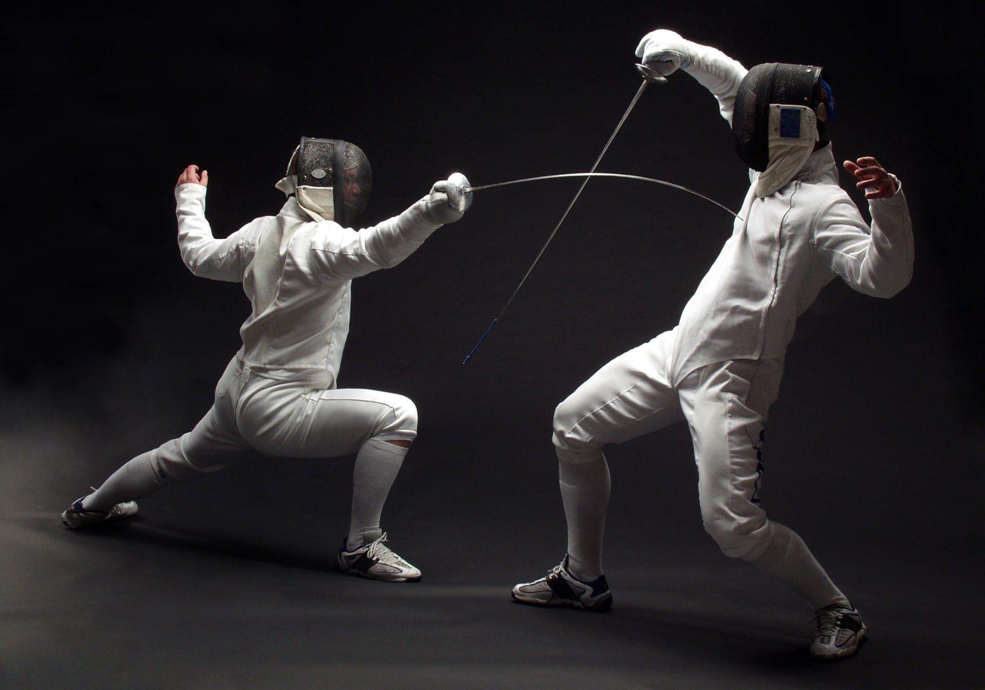 Two fencers. One thrusts whilst the other parries, their foils meeting