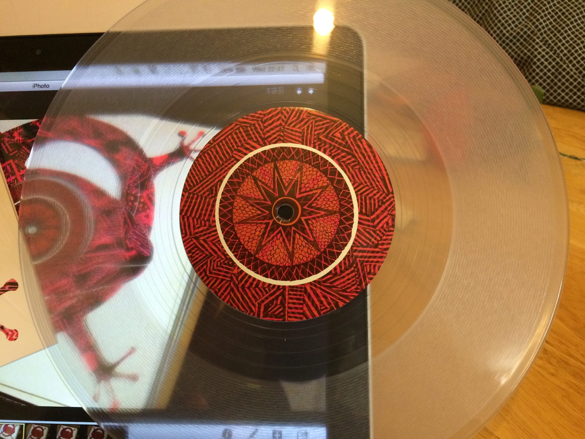 closeup of the clear vinyl 10" with the side A lizard eye label; blurred in the background is a MacBook Pro with more photos of the 10" on it and to the left you can see a corner of the record cover.