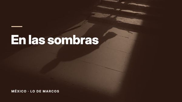 La sombra alargada de una persona sobre el pavimento iluminado al pie de unos escalones de piedra, rodeada de oscuridad. Texto: «En las sombras», México: Lo de Marcos.