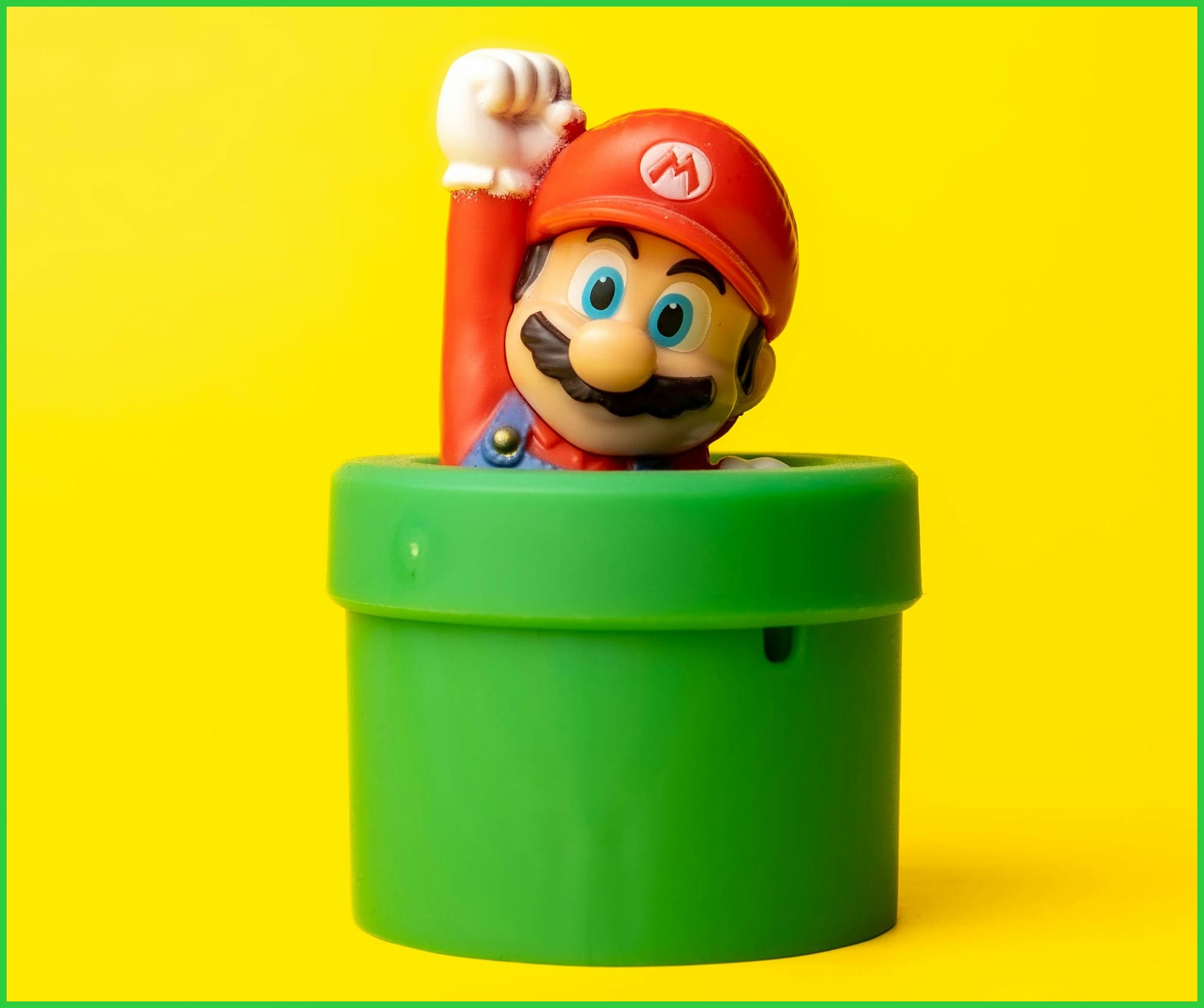 a toy mario in a green container on a yellow background