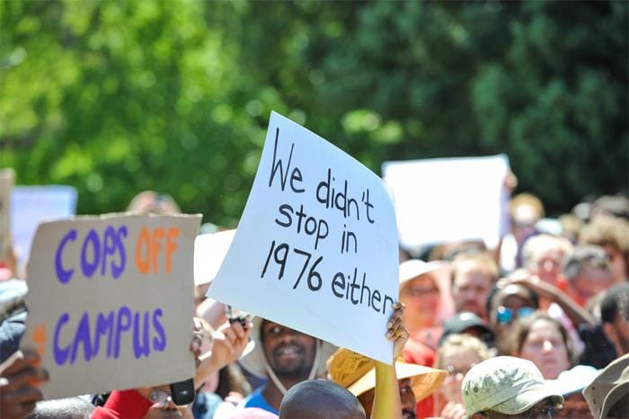 Protester holding a sign that reads We didn’t stop in 1976 either