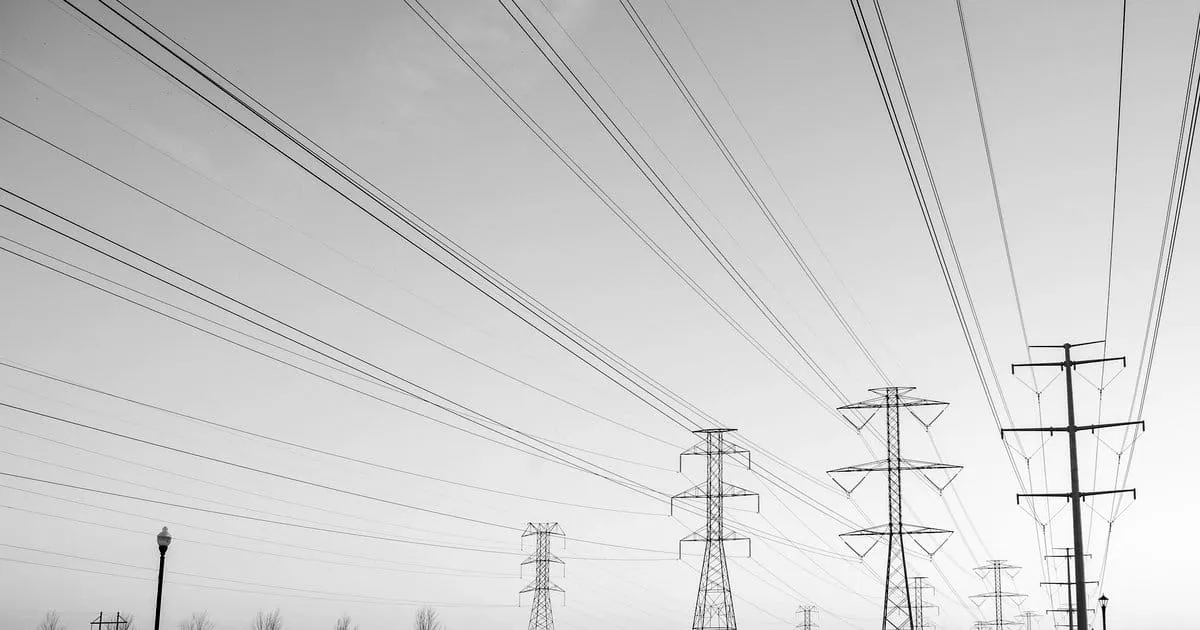 Transmission towers and power lines stretching across an open sky.