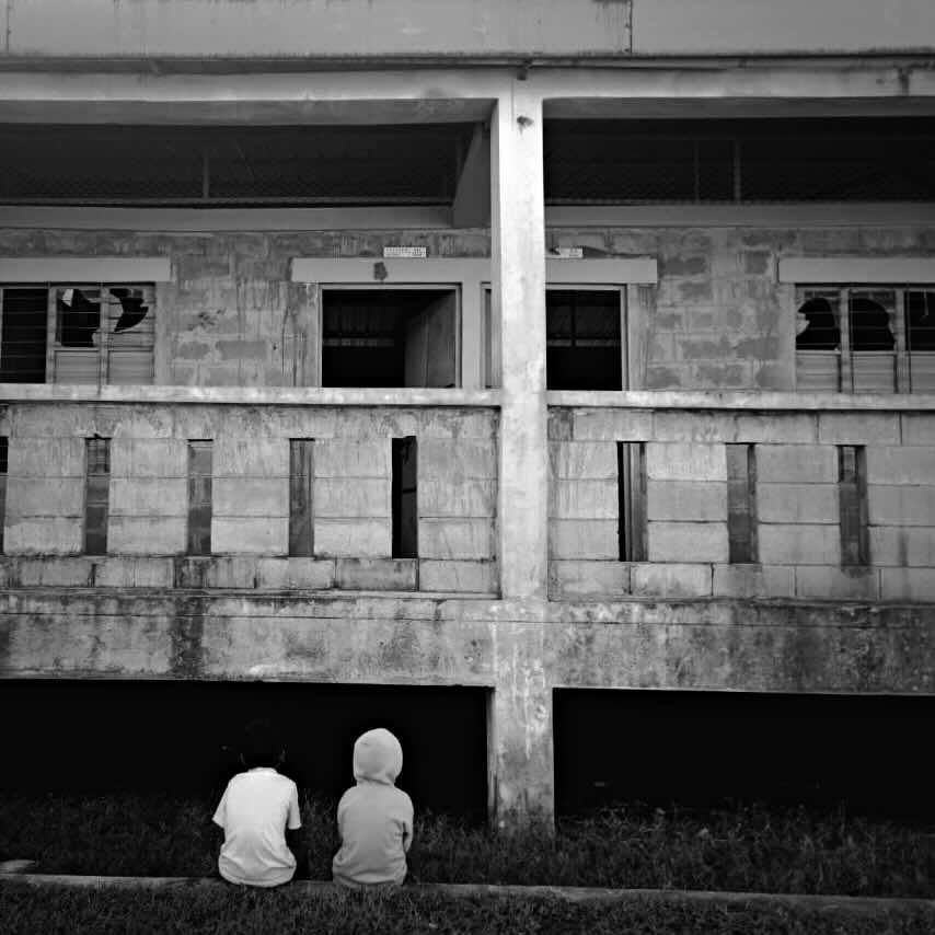 Image of two children sitting of a building in Bhasan Char. 