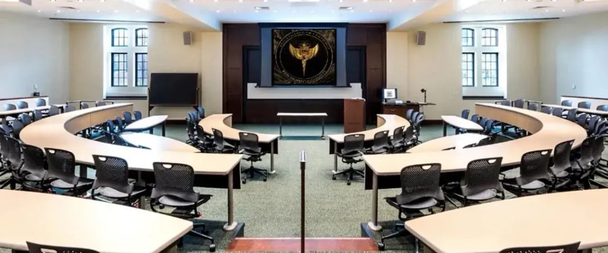 Fake classroom setting with a logo in the middle on a screen.