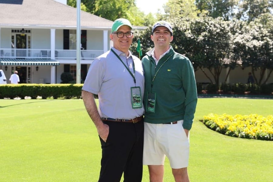 Greg Chambers and son posing for a pic in front of Augusta National's big house