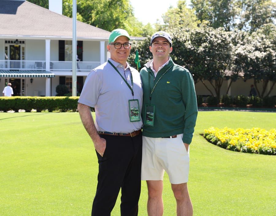 Greg Chambers and his son at the 2026 Masters in front of the big house