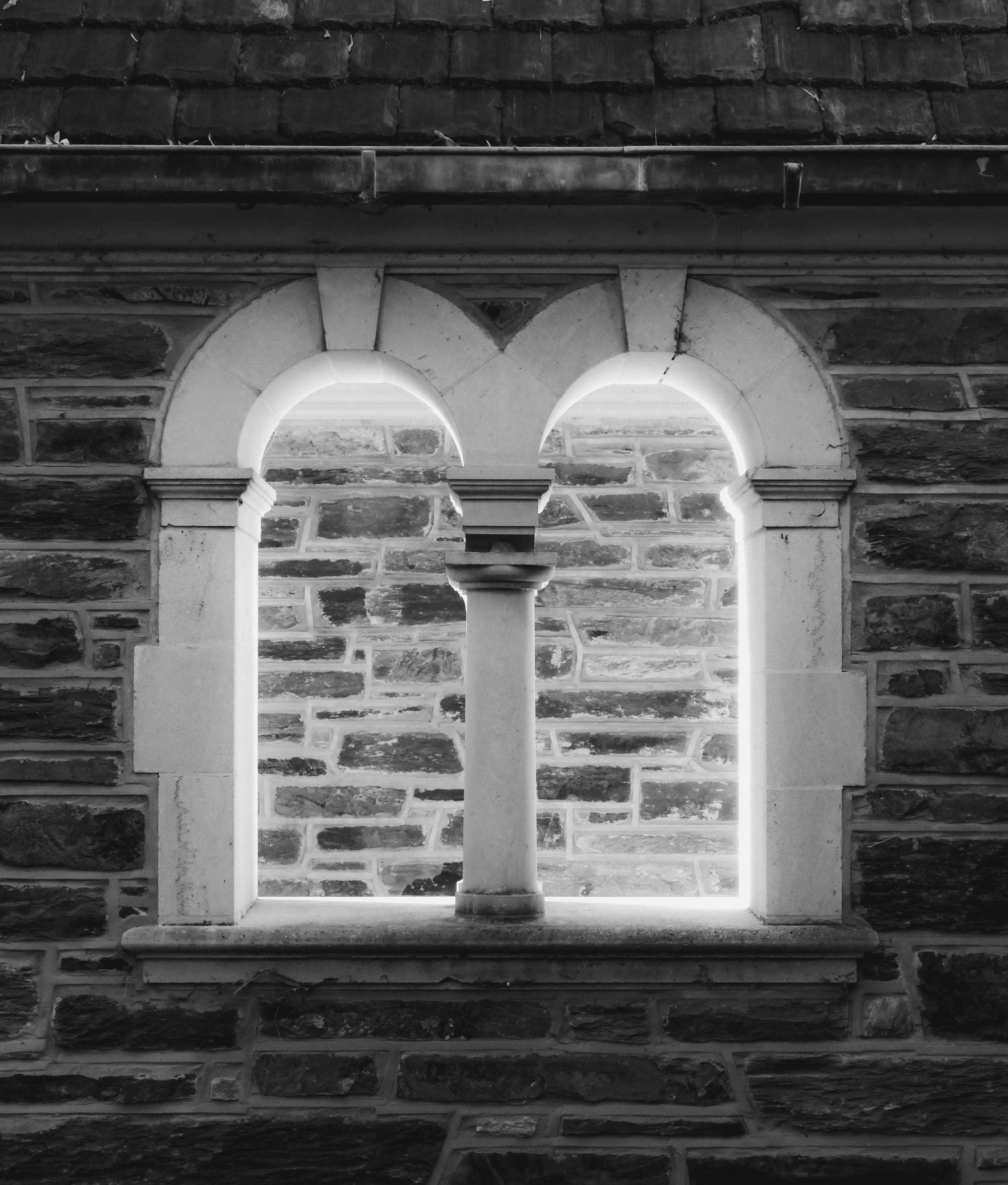 A black and white photo of a window in a brick building