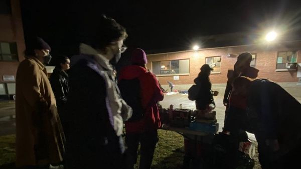 Image of a bunch of people standing around a table of free stuff outside an emergency shelter