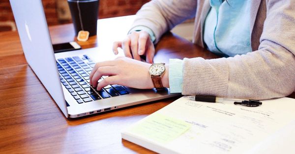 Person typing on a laptop at a wooden desk