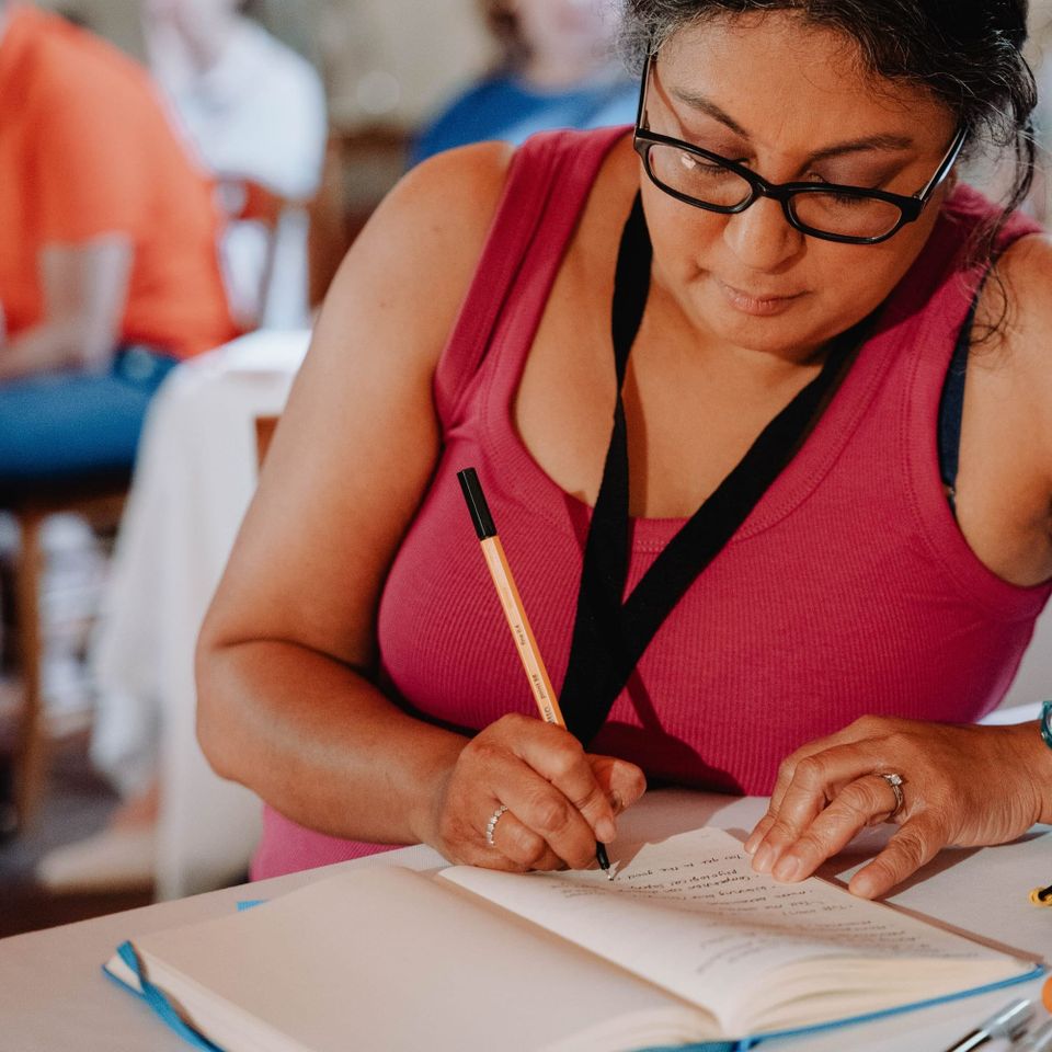 Author has a pen and a notebook and is sat writing in her book