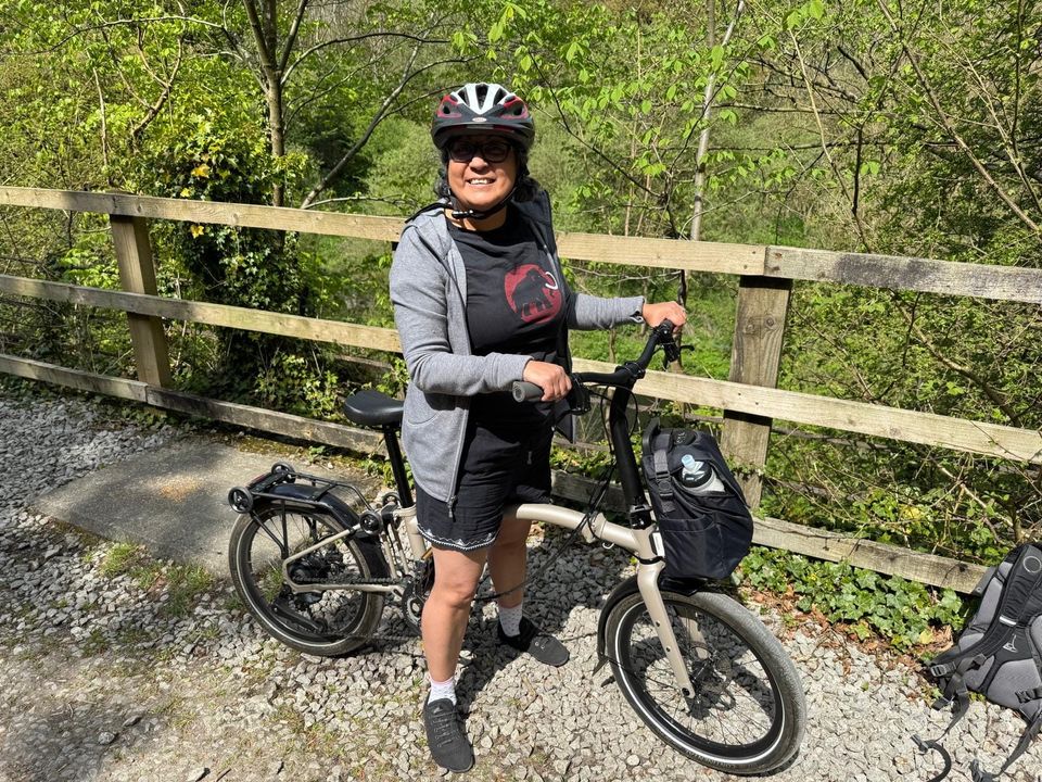 Angel is on her white brompton bike with a happy face as she has just cycled to the end of the trail