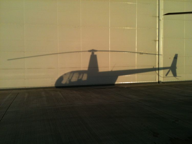 The shadow of a Robinson R44 helicopter on a hangar door