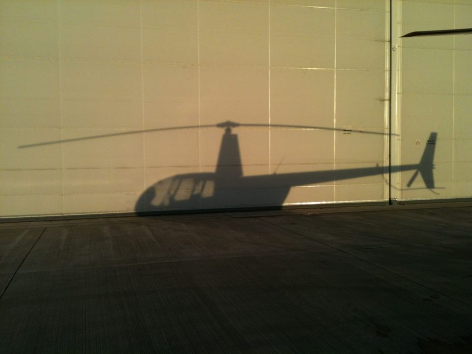 The shadow of a Robinson R44 helicopter on a hangar door