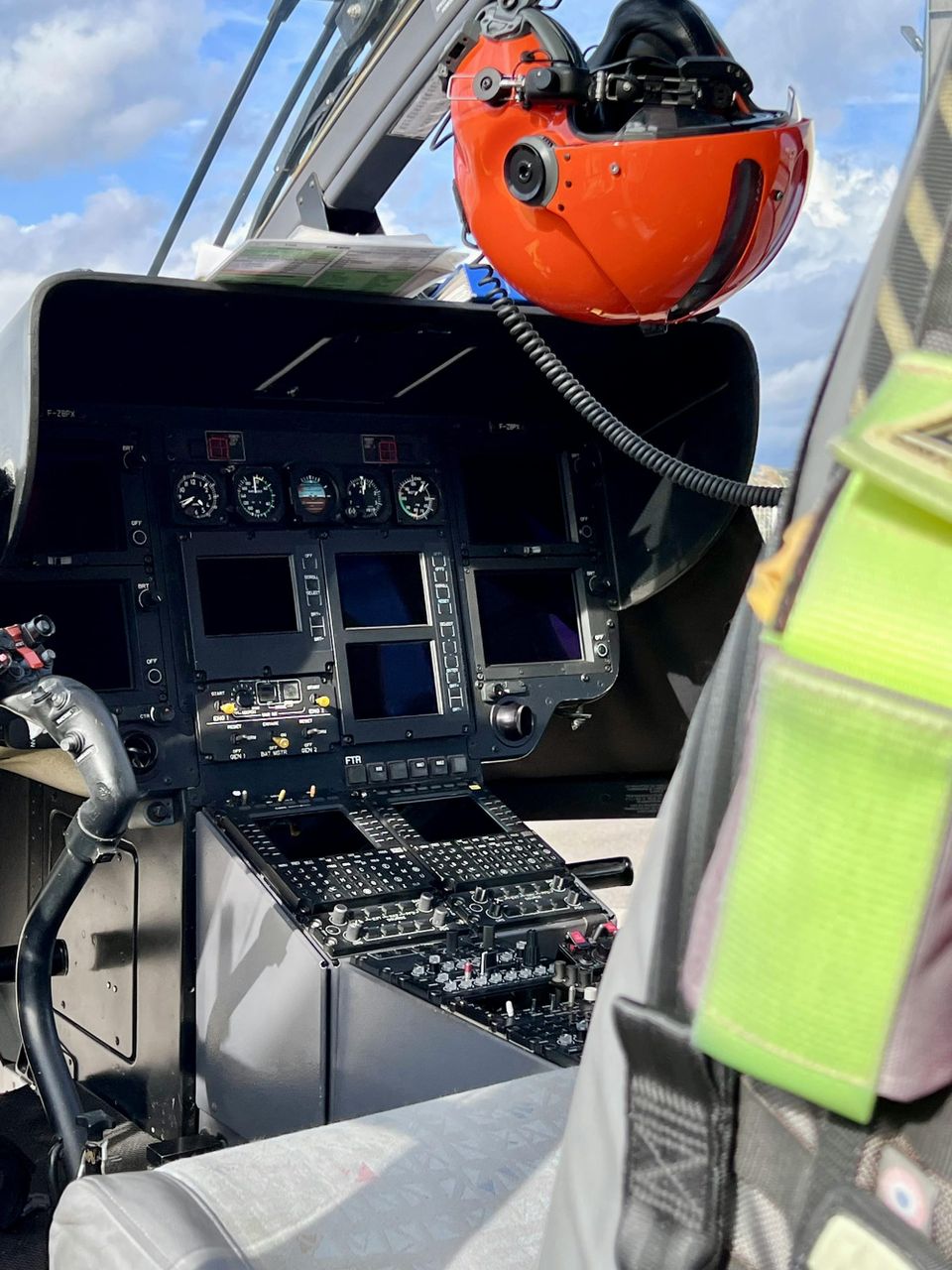 A helicopter cockpit showing a flight helmet hanging above the instrument panel.
