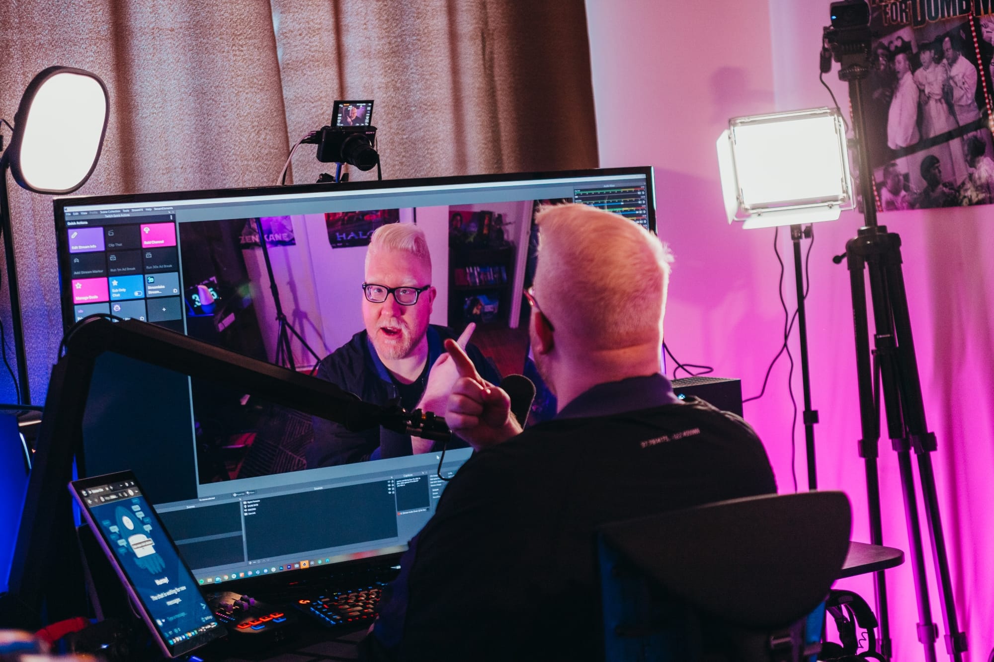 Steve Saylor looks at his computer, a large monitor with a camera and streaming set up.
