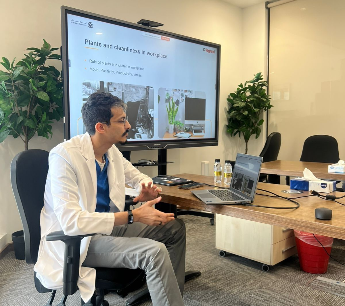 Dr. Yazid Antar leading a workplace health and wellbeing workshop with office chair stretching at Legrand, Riyadh, in partnership with Labayh Business.