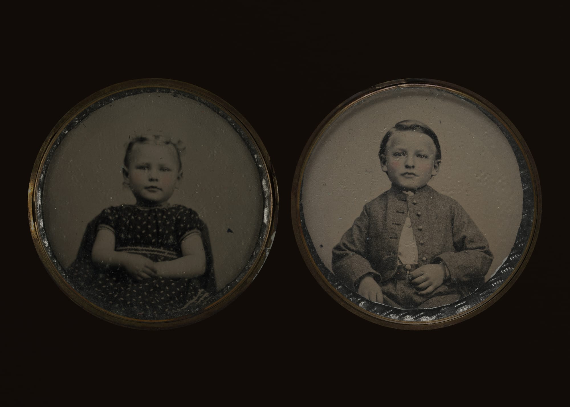 Two circular sepia-toned portraits of young children on a dark background. The left shows a girl in a patterned dress; the right, a boy in a buttoned jacket.