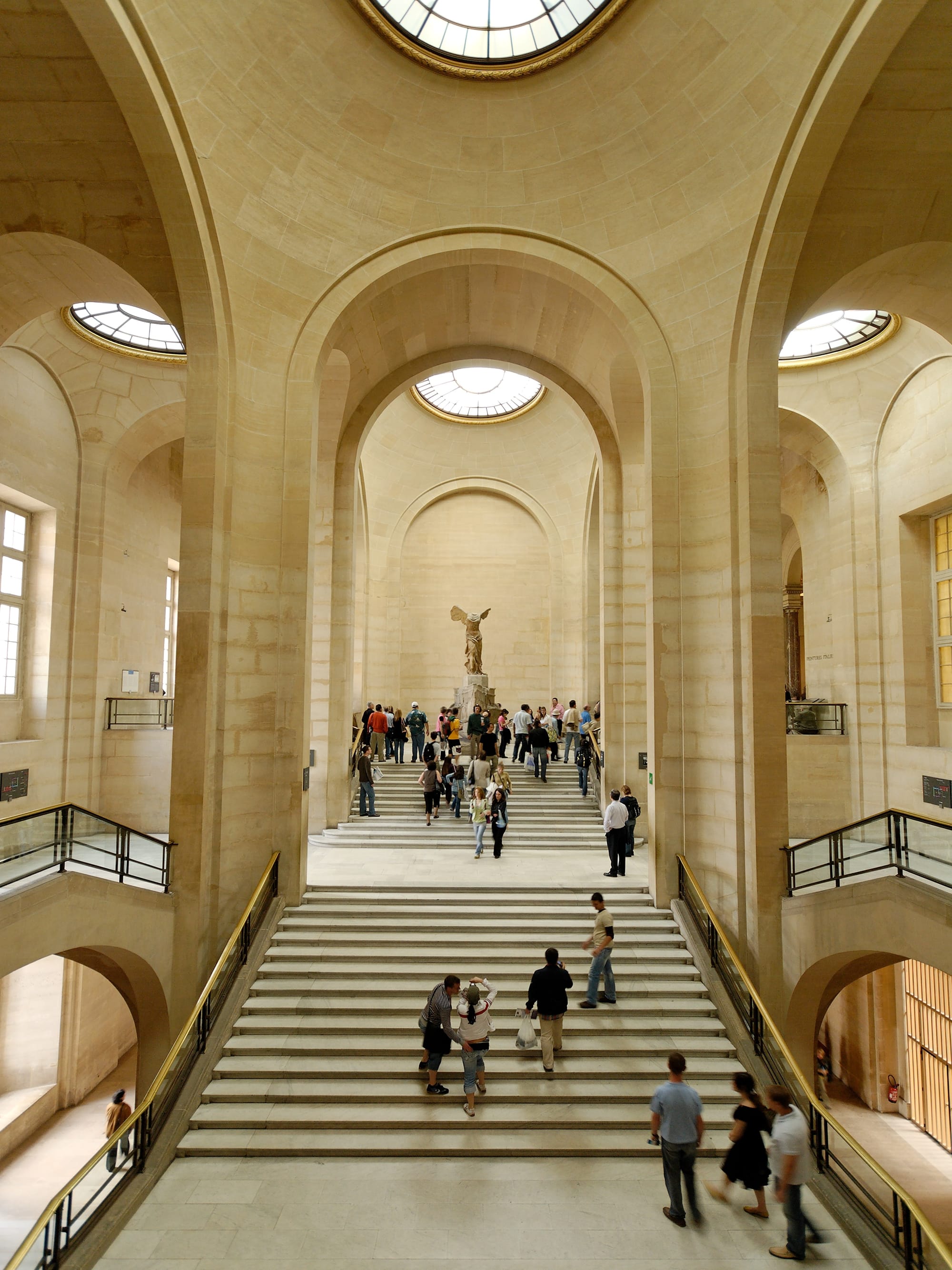 Long view of the space with people grouped around statue