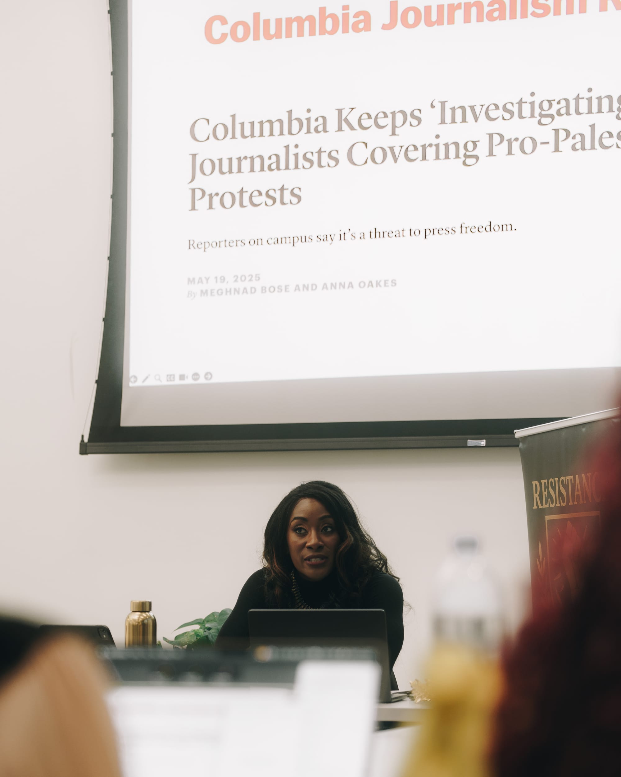 Attiah seated below a screen showing a page from the Columbia Journalism Review, partially visible headline reading "Columbia Keeps 'Investigating' Journalists Covering Pro-Palestinian Protests"