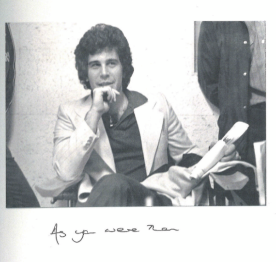 A young, hirsute Jeffrey Epstein in a light jacket and open-necked dark shirt