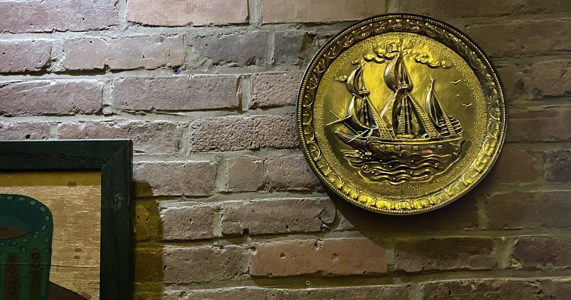 A big embossed brass plaque showing a whaling ship on a wall of weathered brick