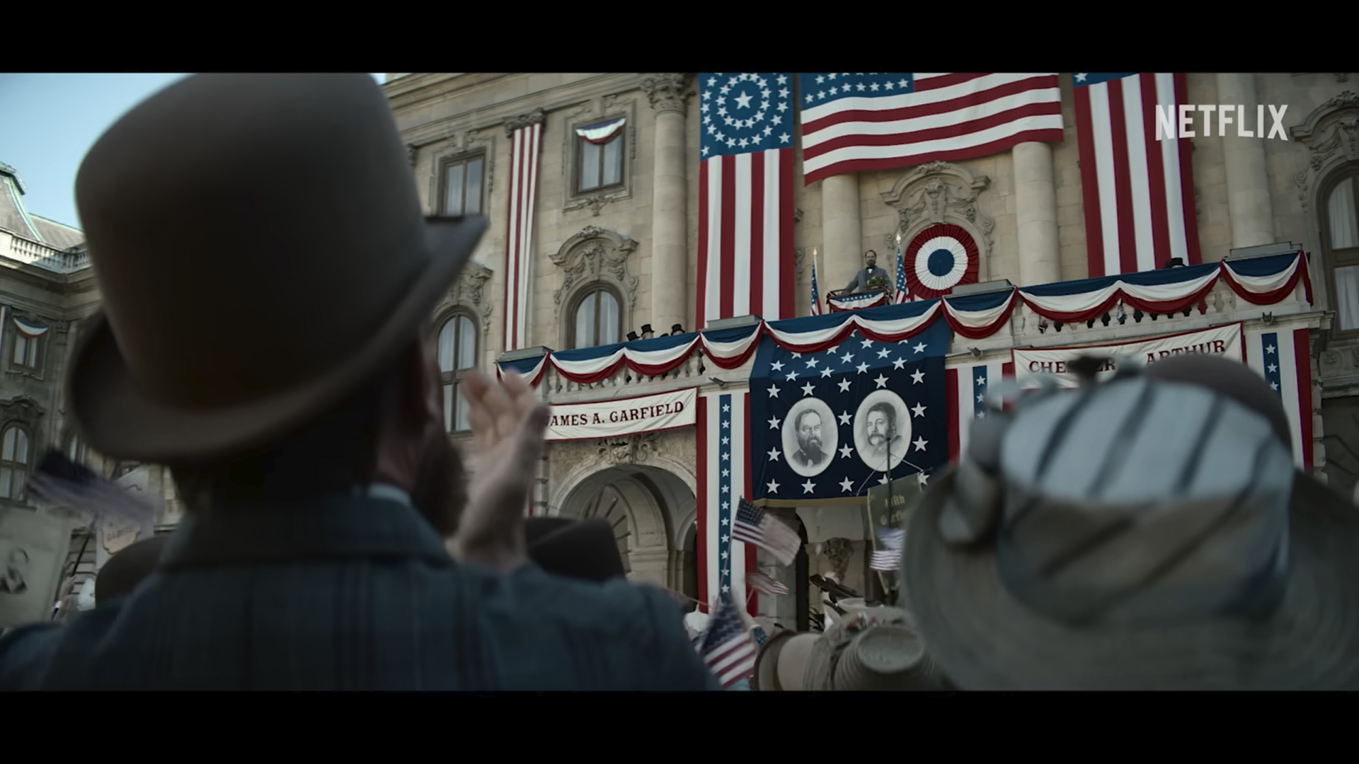 Campaign bunting and banners for James A. Garfield and Chester A. Arthur draped across a building, seen from the crowd assembled before it