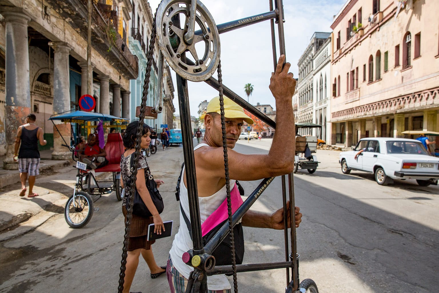 Félix on a city street holding a tall bike.
